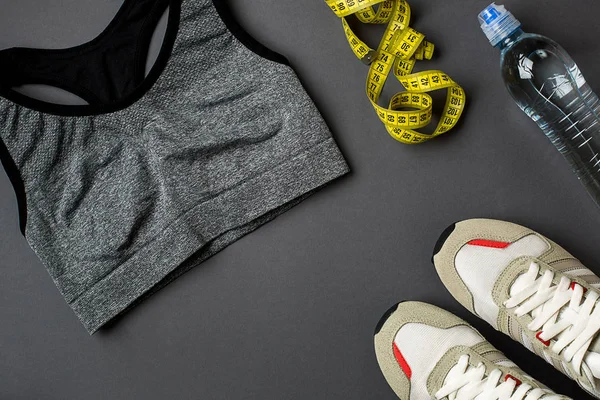 Sporcu kadın giyim ve şişe suyu ile koyu gri arka plan ayarla