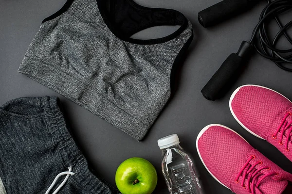 Sportler mit Frauenkleidung, Turnschuhen und Wasserflasche auf grauem Hintergrund — Stockfoto