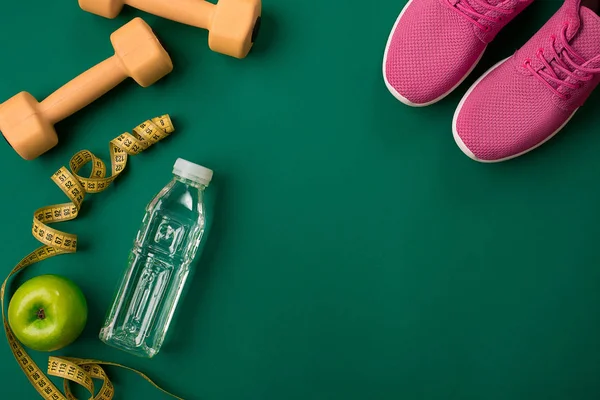 Plano de treino com alimentos e equipamentos de fitness em fundo verde, vista superior — Fotografia de Stock