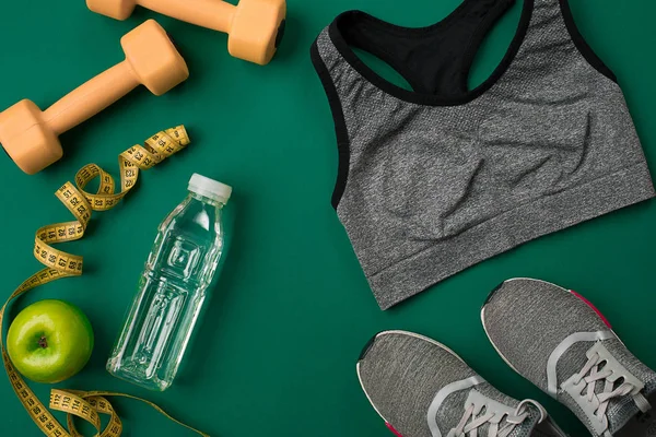 Workout plan with fitness food and equipment on green background, top view