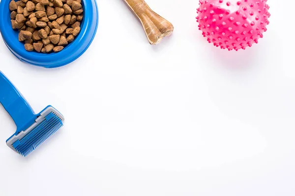 Dry pet food in bowl and toys for dogs on white background top view — Stock Photo, Image