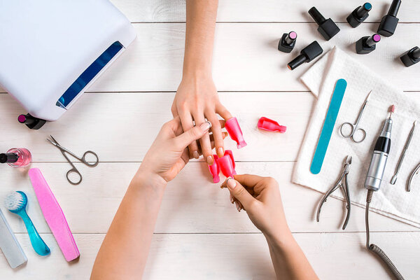 Nail care. Closeup of female hands filing nails with professional nail file in beauty nail salon. Top view