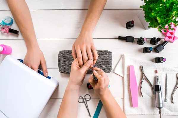 Tırnak bakımı. Güzellik salonunda tırnaklarını profesyonel tırnak törpüsüyle törpüleyen kadın elleri. Üst görünüm