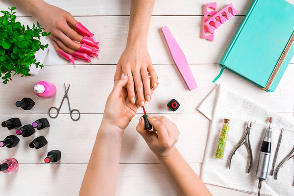 Closeup shot of a woman in a nail salon receiving a manicure by a beautician with nail file. Woman getting nail manicure.