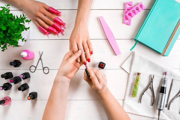 Nail care. Closeup of female hands filing nails with professional nail file in beauty nail salon. Top view