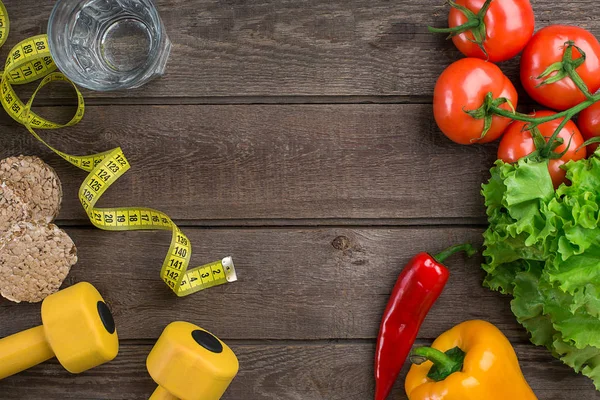 Desporto e dieta. Legumes, halteres e centímetro. Pimentos, tomates, salada em fundo rústico — Fotografia de Stock