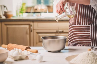 Genç kadın ile hamur, bir kase içine yağ boşaltma yakın çekim
