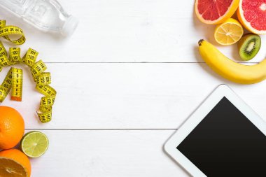 Yulaf ezmesi, taze meyve ve şişe suyu rustik ahşap masa tablete ile sağlıklı kahvaltı.
