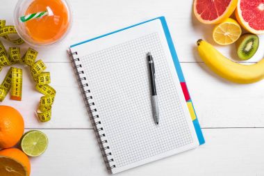 Cam düşük narenciye - limon, greyfurt, portakal, defter kalem Beyaz ahşap zemin üzerinde ile taze meyve suyu