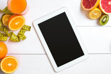 Cam düşük narenciye - limon, greyfurt, portakal, tablet Beyaz ahşap zemin üzerine taze meyve suyu