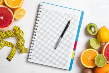 Cam düşük narenciye - limon, greyfurt, portakal, defter kalem Beyaz ahşap zemin üzerinde ile taze meyve suyu
