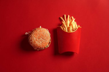 Hamburger ve patates kızartması kırmızı zemin üzerine sahte kavramı. Kopya alanı için metin ve logosu.