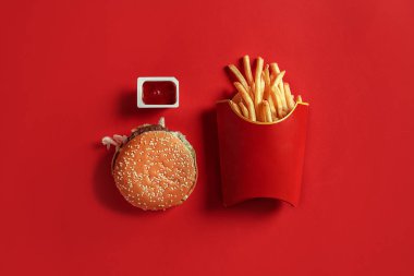 Hamburger ve patates kızartması. Hamburger ve kızarmış patates kırmızı kağıt kutusunda. Fast food kırmızı zemin üzerine.