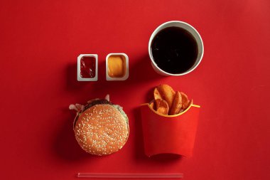 Hamburger, patates, sos ve içki kırmızı zemin üzerine sahte kavramı. Kopya alanı için metin ve logosu.