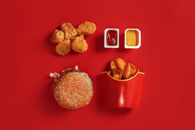 Hamburger ve patates kızartması. Hamburger ve kızarmış patates kırmızı kağıt kutusunda. Fast food kırmızı zemin üzerine.