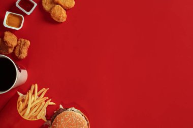 Hamburger ve patates kızartması. Hamburger ve kızarmış patates kırmızı kağıt kutusunda. Fast food kırmızı zemin üzerine.
