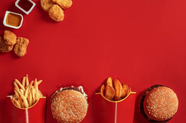 Hamburger ve patates kızartması. Hamburger ve kızarmış patates kırmızı kağıt kutusunda. Fast food kırmızı zemin üzerine.