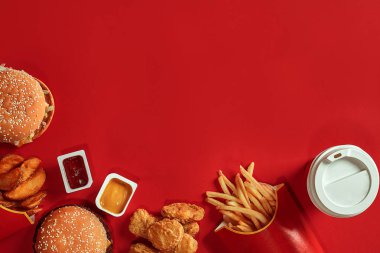 Hamburger ve patates kızartması. Hamburger ve kızarmış patates kırmızı kağıt kutusunda. Fast food kırmızı zemin üzerine.