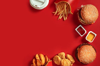 Fast food yemek üstten görünüm. Et burger, patates cipsi ve bardak içki kırmızı zemin üzerine. Paket servisi olan restoran kompozisyon.