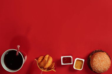 Hamburger, patates, sos ve içki kırmızı zemin üzerine sahte kavramı. Kopya alanı için metin ve logosu.