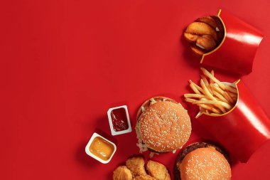 Fast food yemek üstten görünüm. Et burger, patates cipsi ve nuggets kırmızı zemin üzerine. Paket servisi olan restoran kompozisyon.