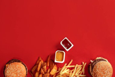 Fast food yemek üstten görünüm. Et burger, patates cipsi ve nuggets kırmızı zemin üzerine. Paket servisi olan restoran kompozisyon. Üstten Görünüm
