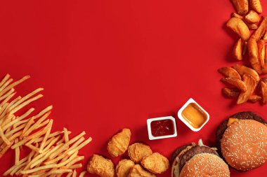Fast food yemek üstten görünüm. Et burger, patates cipsi ve nuggets kırmızı zemin üzerine. Paket servisi olan restoran kompozisyon.