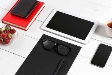 Modern çalışma alanı ile dijital tablet bilgisayar ve cep telefonu, fincan kahve, kalem ve boş kağıt sayfası.