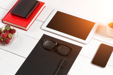 Modern çalışma alanı ile dijital tablet bilgisayar ve cep telefonu, fincan kahve, kalem ve boş kağıt sayfası.