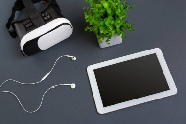 Sanal gerçeklik gözlükleri ve tablet kulaklıklar üzerinde gri bir arka plan ile. Üstten Görünüm