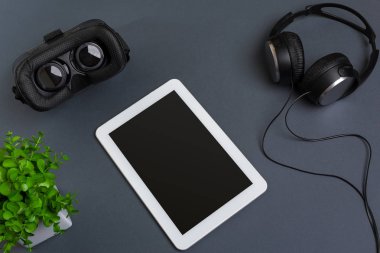 Sanal gerçeklik gözlükleri ve tablet kulaklıklar üzerinde gri bir arka plan ile. Üstten Görünüm
