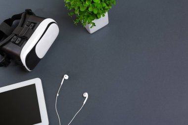 Sanal gerçeklik gözlükleri ve tablet kulaklıklar üzerinde gri bir arka plan ile. Üstten Görünüm