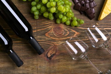 Kırmızı ve beyaz şarap şişeleri, üzüm, peynir ve ahşap masa üzerinde gözlük. Kopya alanı ile Üstten Görünüm