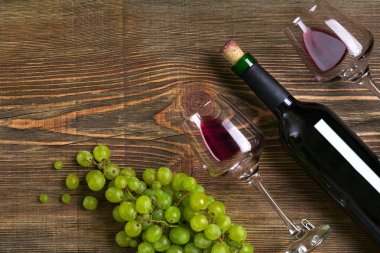 Kırmızı şarap şişesi, üzüm, çikolata ve ahşap masa üzerinde gözlük. Kopya alanı ile Üstten Görünüm