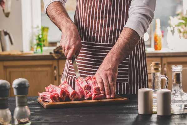 Adam ahşap kesme tahtası ev mutfakta taze et parçası keser