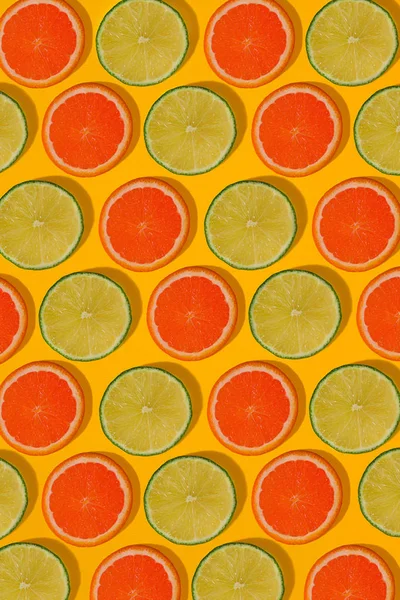 Grapefruity a limetky vzorek na žlutém podkladu. Minimální plochou ležel koncept. — Stock fotografie