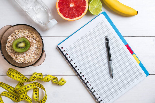 Свежие фрукты с лентой мера на белом деревянном фоне. Вид сверху
