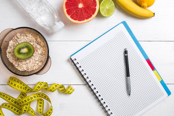 Здоровый завтрак с овсянкой, свежими фруктами и бутылкой воды с ноутбуком на деревенском деревянном столе
.