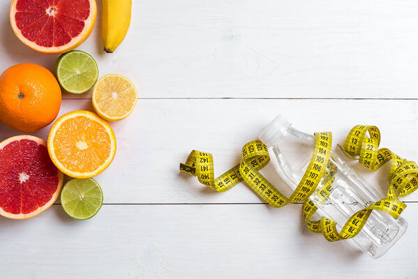 Свежие фрукты с лентой мера на белом деревянном фоне. Вид сверху
