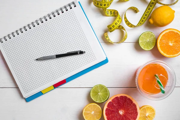 Vers sap in glas van citrusvruchten - citroen, grapefruit, sinaasappel, notebook met potlood op wit houten achtergrond — Stockfoto