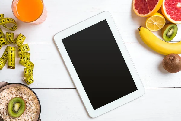Cam düşük narenciye - limon, greyfurt, portakal, tablet Beyaz ahşap zemin üzerine taze meyve suyu