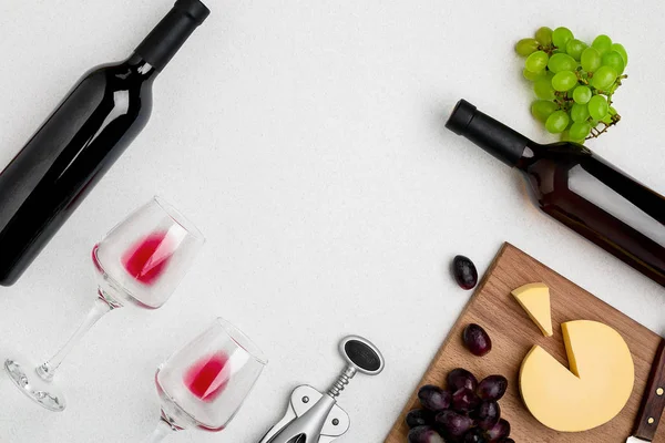 Dos copas de vino con vino tinto, botella de vino tinto y queso sobre fondo blanco.Vista horizontal desde la parte superior . — Foto de Stock