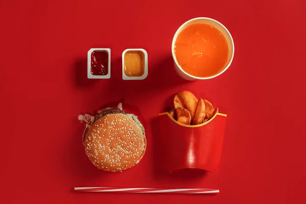 Бургер і чіпси. Гамбургер і картопля фрі в червоній паперовій коробці. Фастфуд на червоному тлі . — стокове фото