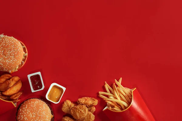 Burger and Chips. Hamburger and french fries in red paper box. Fast food on red background.