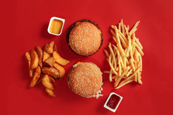 Hamburger ve patates kızartması. Hamburger ve kızarmış patates kırmızı kağıt kutusunda. Fast food kırmızı zemin üzerine. — Stok fotoğraf