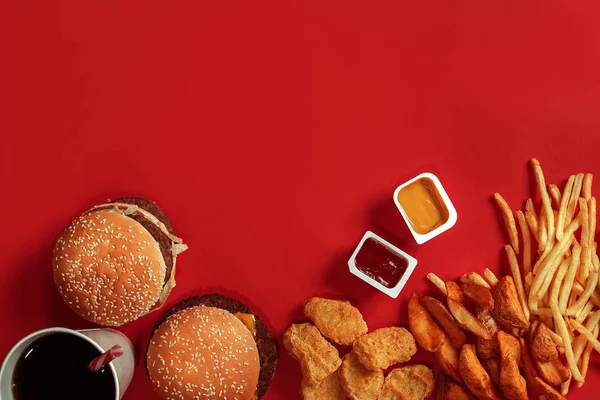 快餐菜顶视图。肉汉堡，薯条和饮料在红色背景上的玻璃。外卖的组成. — 图库照片