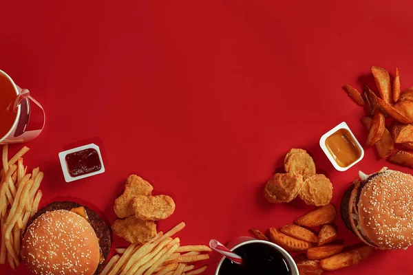 Hamburger ve patates kızartması. Hamburger ve kızarmış patates kırmızı kağıt kutusunda. Fast food kırmızı zemin üzerine.