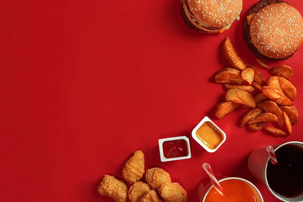 Fast food yemek üstten görünüm. Et burger, patates cipsi ve bardak içki kırmızı zemin üzerine. Paket servisi olan restoran kompozisyon. — Stok fotoğraf