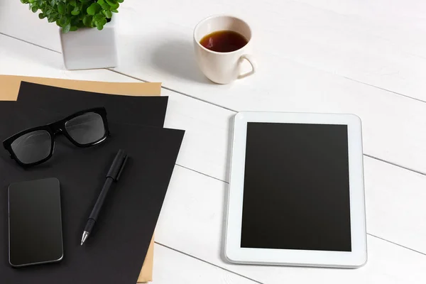 Tablet, blank sheet, glasses and coffee cup on office wooden table