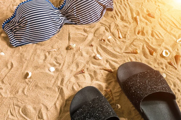 Summer bikini and accessories stylish beach set, Beach bikini summer outfit and sea sand as background, Top View, Concept